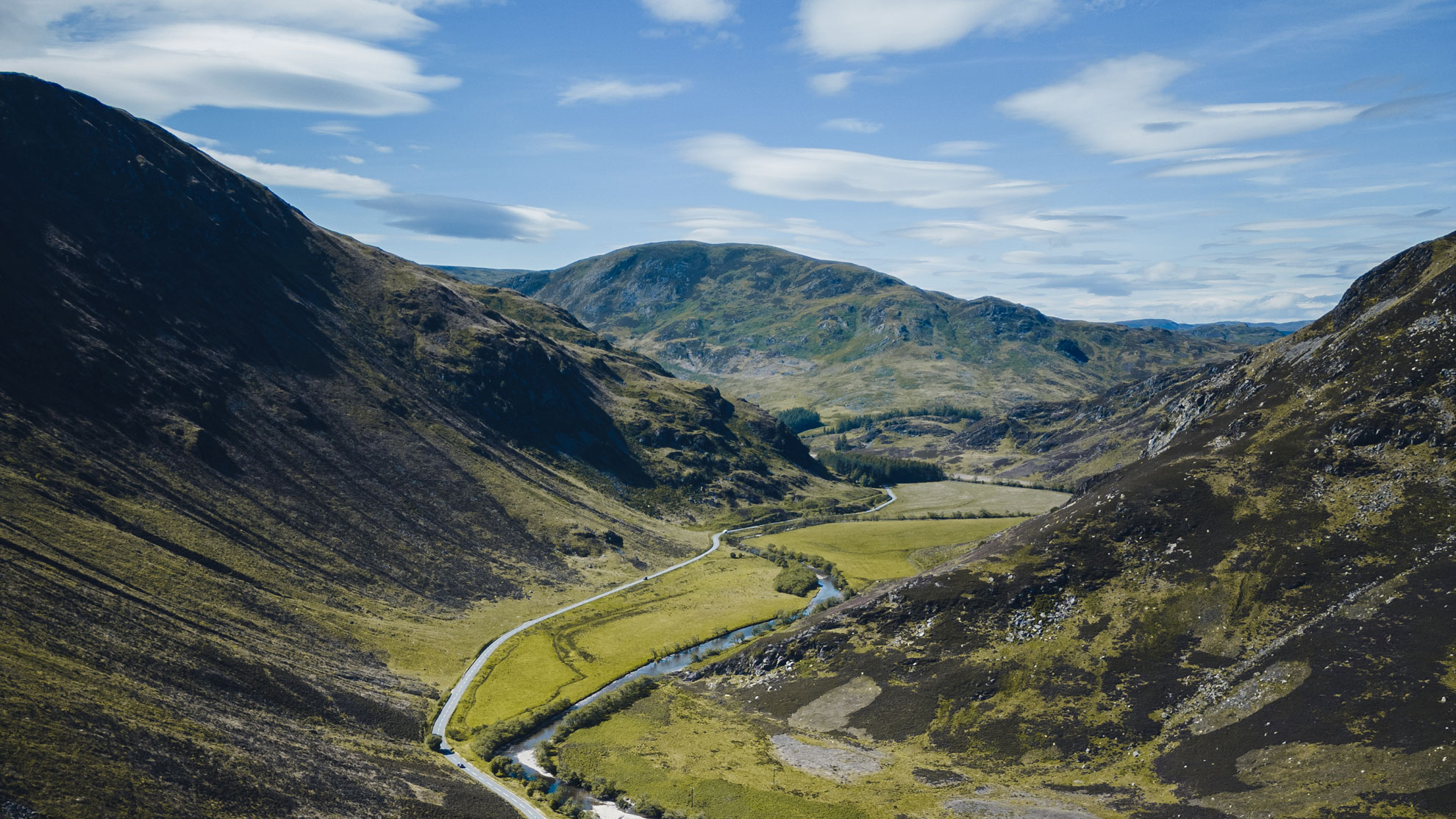 Sma' Glen valley stretching between rolling green hills under a bright blue sky